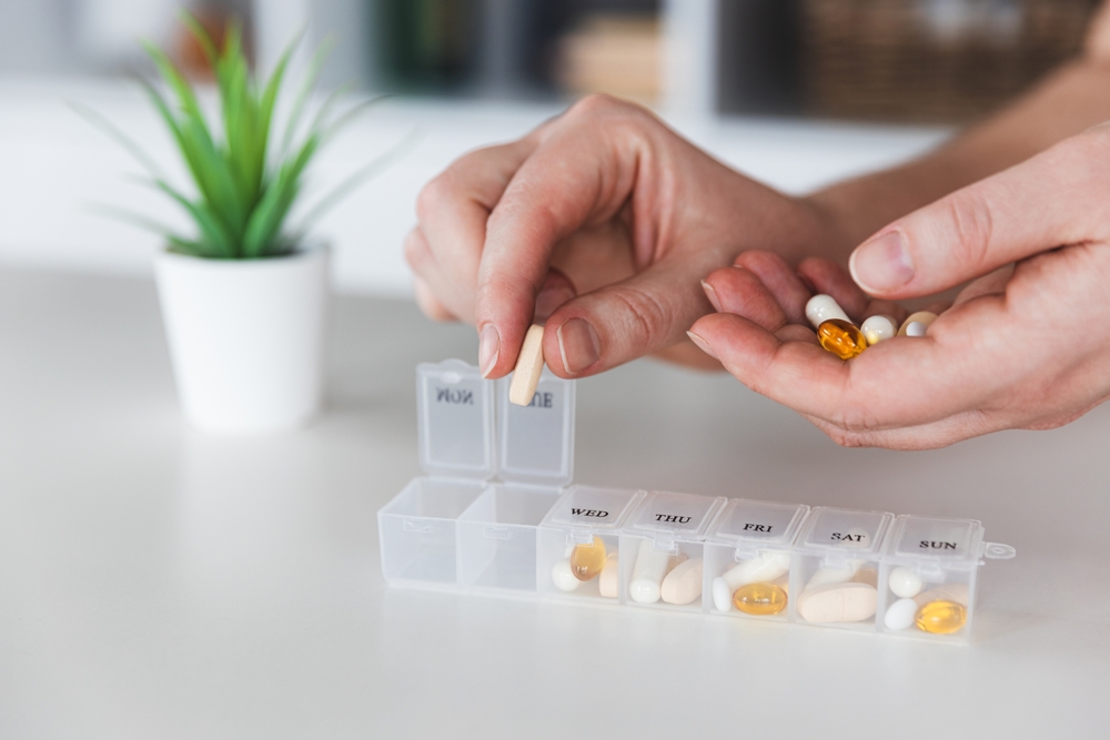 Elderly hands organizing pet medication into a weekly pill organizer for a dog or cat's treatment plan