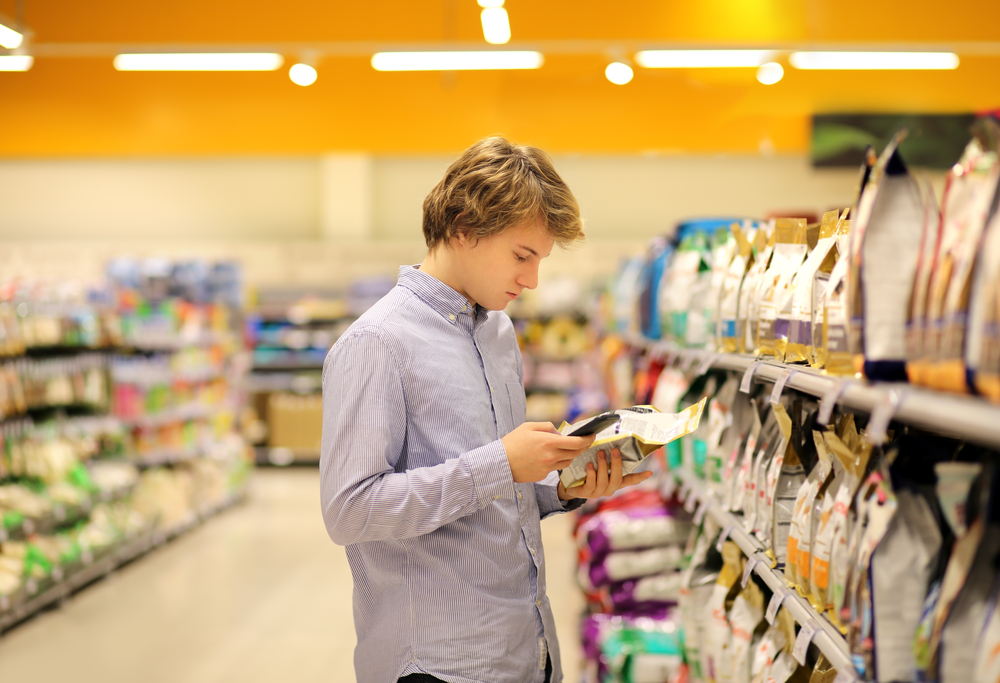 Pet owner using a smartphone to research pet food labels while shopping at a grocery store